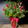 Red roses in a clear glass vase with a pink ribbon