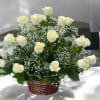 Cream roses arranged in a wicker basket with baby's breath