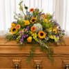 A bright, garden-inspired casket spray that brings warmth and celebration to a