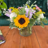 A sweet, delicate arrangement in a low cylinder vase featuring white roses