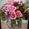A cube vase with alstroemeria, pink roses, spray roses and carnations