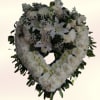 A white heart-shaped wreath crafted for sympathy and remembrance, this funeral floral