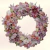 A heart-shaped wreath overflowing with lilies, roses, carnations and daisies creates an