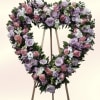 A heart-shaped sympathy arrangement in soft pinks and purples, mounted on a