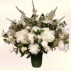 A serene cluster of white roses, carnations, chrysanthemums and snapdragons gives this