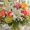 Crisp white lilies paired with peach roses and fresh hydrangeas create a