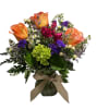 Bouquet of orange and pink roses in a glass vase with a ribbon