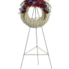 Standing funeral wreath with red and white flowers and blue accents on an easel