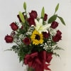 Bouquet of red roses, a white lily, and a sunflower in a glass vase