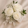 A simple and sophisticated corsage crafted with pristine white roses, delicate baby&rsquo;s