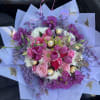 Round bouquet of pink and purple flowers with chocolates in lavender wrapping paper