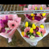 Three mixed bouquets with pink gerberas, tulips, and roses in pink and white wrap