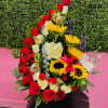 Tall floral arrangement with red and white roses and yellow sunflowers in a basket
