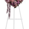 Heart-shaped pink floral wreath on a white easel with ribbon