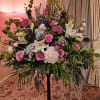 Large mixed floral arrangement on a stand with pink, white, and purple blooms
