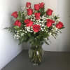 Red roses arranged in a clear glass vase with white baby's breath
