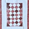 Patchwork quilt with a diamond pattern in pink, red, and white