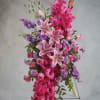 Tall arrangement of pink lilies, roses, and purple flowers