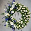 Large floral wreath with white calla lilies and blue flowers on a stand