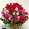 Basket arrangement of red, pink, and lavender roses displayed on a marble surface