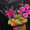 Neon hot-pink gerbera daisies and vibrant orange roses and tulips create an