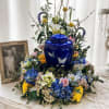 A glossy cobalt-blue ceramic urn with delicate butterfly motifs anchors this commemorative