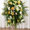 Soft golden roses and pure white lilies form a dignified standing spray