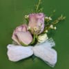 Boutonniere with lavender roses and a white ribbon bow