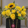 Yellow roses and a sunflower arranged in a black gift box with a gold chain.