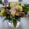 Bouquet of cream and mauve roses with pale carnations in a glass vase