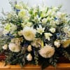 Large white floral spray on a wooden casket