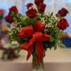Red roses in a glass vase with baby's breath and a large red ribbon
