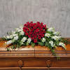 Red rose casket spray with white flowers on a wooden casket