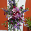 Tall floral spray with pink lilies and purple flowers on a stand