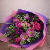 Bouquet of pink roses and purple flowers wrapped in pink and purple paper