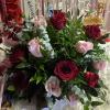 Red and pale pink roses arranged with greenery in a tall centerpiece