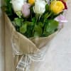 Wrapped bouquet of red, white, yellow, and pink roses in patterned paper with a white ribbon
