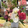 Mixed bouquet of pink roses, white orchids, and purple blooms in a square vase