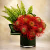 A striking tropical luxury arrangement featuring vibrant red pincushion protea designed with