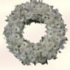 A softly composed circular wreath of white daisies, lilies, and rose buds
