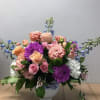 Mixed pink, purple, and blue flowers in a white vase