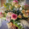 A cheerful garden-inspired arrangement featuring romantic roses, delicate spray roses, soft seasonal