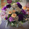 A romantic garden-inspired arrangement featuring soft peach roses, rich plum and lavender