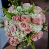 Pink roses and white flowers arranged in a hand-held bouquet