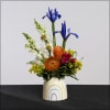 A happy, ceramic container with a mix of summery flowers, including snapdragons