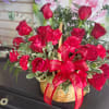 Red roses and carnations in a wicker basket with a red ribbon