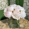 White and pale pink peonies arranged in a clear glass vase