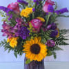 Bursting with sunshine yellows and graceful purples, this arrangement reflects the happiness