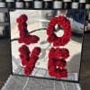 Red roses arranged as the numbers 1, 0, 1, and 5 in a mirrored frame