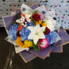 Mixed bouquet with blue hydrangeas, red roses, sunflowers, and a small teddy bear